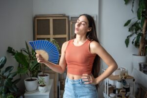 A woman fanning herself indoors.